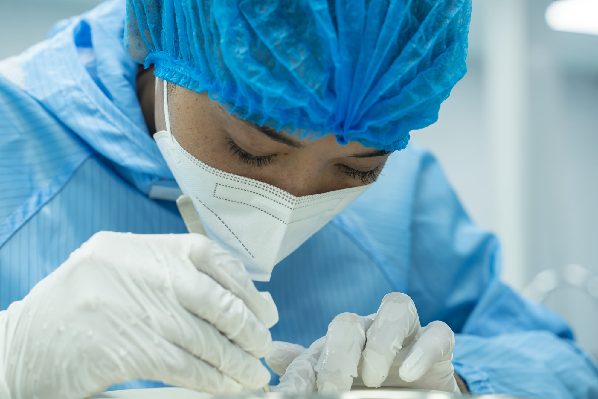 Team member in PPE hand-cleaning edible bird's nest at the NIS NEST factory, Cambodia