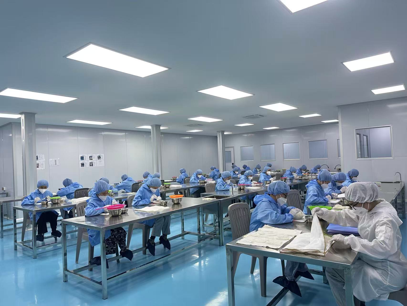 NIS NEST factory floor in Cambodia: workers in PPE hand-cleaning nests at stainless steel tables